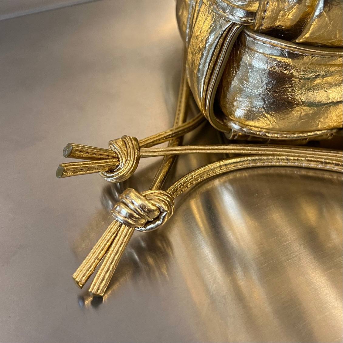 BOTTEGA VENETA SMALL CASSETTE BUCKET 18 IN GOLD METALLIC SOFT LAMBSKIN